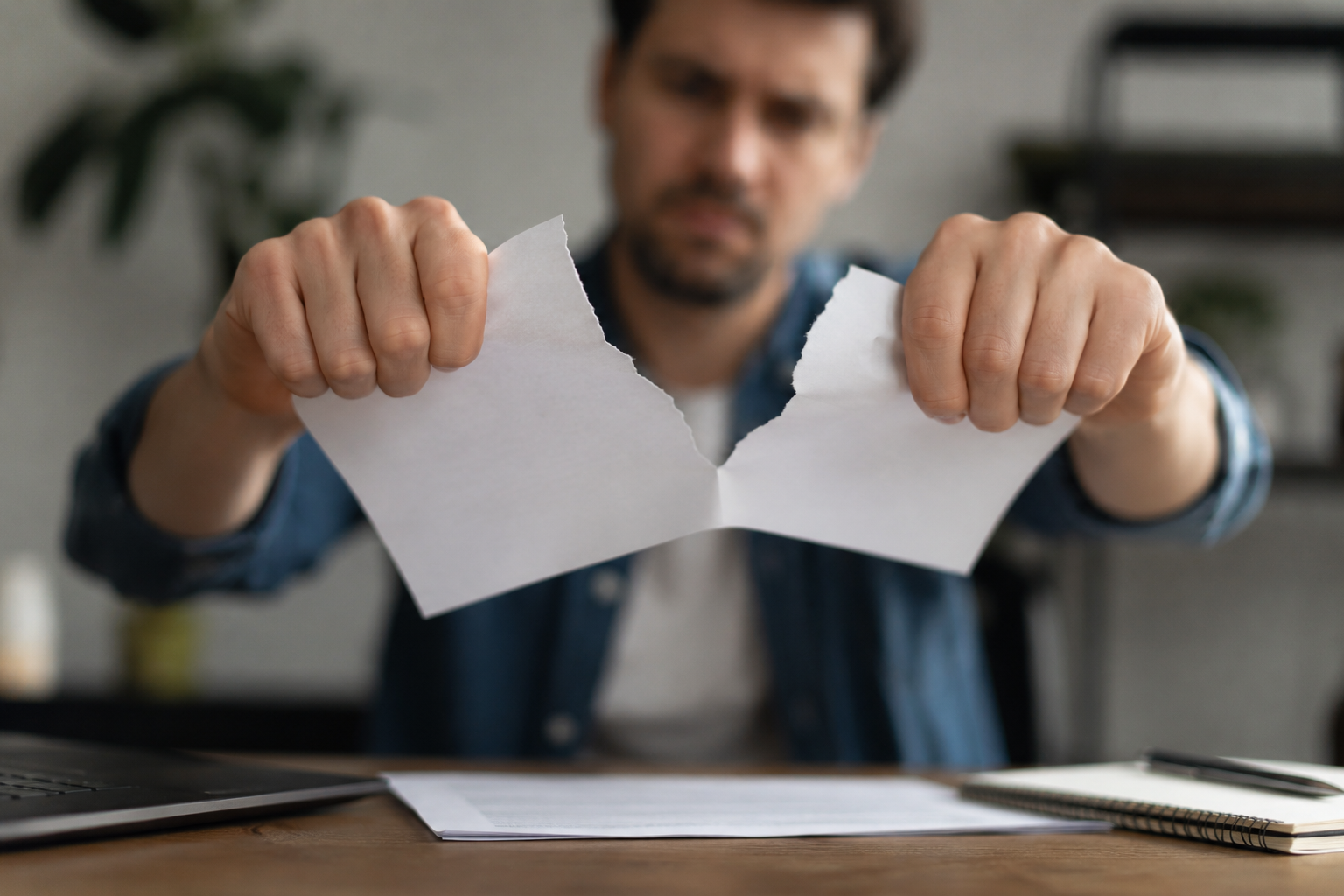 A man ripping up a piece of paper at his desk